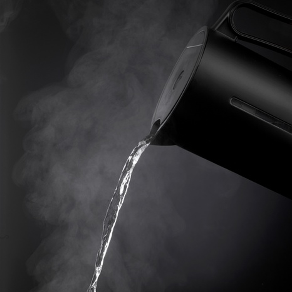 Schwarzer Wasserkocher kippt heisses Wasser